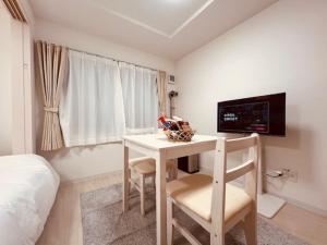1 dormitorio con mesa y TV en la pared en Raffine103, en Sapporo