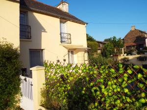 a white house and a fence with a hedge at Broceliande gite maison equipee 3 grandes chambres, chez papy et mamie in Loyat