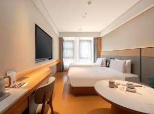 Habitación de hotel con 2 camas, mesa y TV. en Ji Hotel Shanghai Caolu China Merchants Garden City, en Shanghái