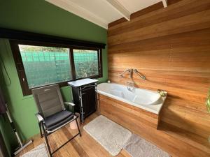 y baño con bañera y silla. en Peony Place, en Ciudad del Cabo