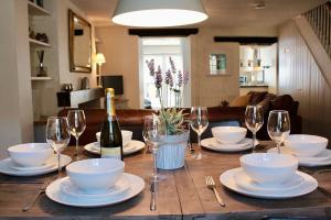 a table with plates and glasses and a bottle of wine at Stylish, central Beaumaris cottage in Beaumaris