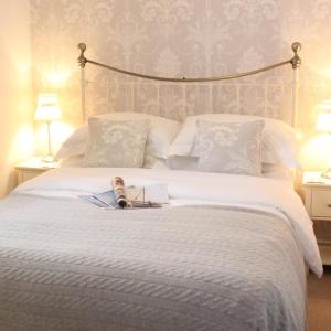 ein Schlafzimmer mit einem weißen Bett mit einem Buch darauf in der Unterkunft Stylish, central Beaumaris cottage in Beaumaris