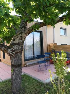 a table and a blue chair next to a tree at La P'tite Créole in Auzon +6 photos