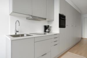 a white kitchen with a sink and a microwave at Tammer Huoneistot - City Suite 6 - Best Location & Great Amenities in Tampere