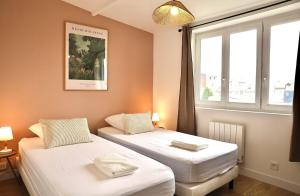 two beds in a room with a window at Appartement - Washington 3 in Le Havre