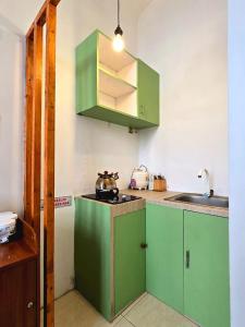 Cottage Linggayoni Dieng في Diyeng: مطبخ مع دواليب خضراء ومغسلة