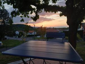 a picnic table sitting under a tree with the sunset at La P'tite Créole in Auzon