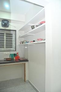 een keuken met witte muren, een aanrecht en planken bij AVO Nest Kondapur - 1 BHK Fully Furnished Penthouse #601 in Kondapur