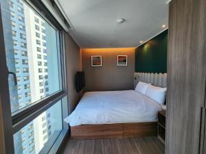a small bedroom with a bed and a large window at Bona Together In Haeundae Residence in Busan +75 photos