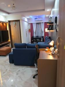 a living room with blue couches and a table at Lakefront Lounge-Luxe 1bhk condo with 2queen beds-2baths in Mumbai