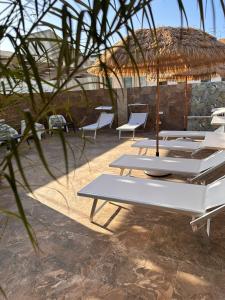 a group of lounge chairs and an umbrella on the beach at B&B "LE CAMERE" Luxury Rooms SIRACUSA in Siracusa