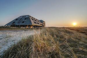 a building sitting on top of a field at sunset at Paal 8 Hotel aan Zee in West aan Zee