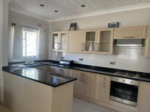 a kitchen with wooden cabinets and a black counter top at Wales Suite in Harare
