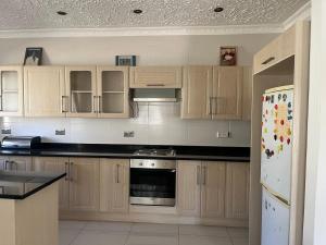 a kitchen with wooden cabinets and a white refrigerator at Wales Suite in Harare