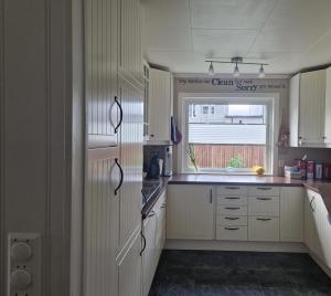 a kitchen with white cabinets and a window at The pink googly eyed house in Tjelta