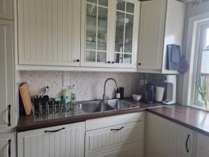 a kitchen with white cabinets and a sink at The pink googly eyed house in Tjelta +18 photos