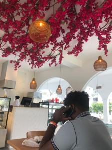 a man talking on a cell phone under a tree with flowers at Santorini 2BR Resort Apt - Negombo Beach & Airport in Negombo +119 photos