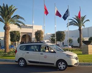 Un pequeño coche blanco aparcado delante de unas banderas. en Tangier Chefchaouen Express Express Tanger Chefchaouen, en Tánger