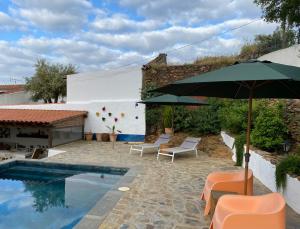 a patio with chairs and an umbrella next to a pool at Montado Village in Portel