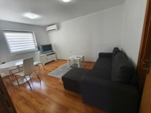a living room with a black couch and a table at Depandans Stefan in Nevesinje