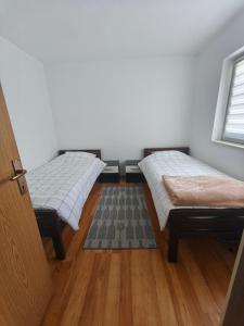 two beds in a room with a wooden floor at Depandans Stefan in Nevesinje