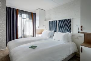 a large white bed in a room with a window at Paal 8 Hotel aan Zee in West aan Zee