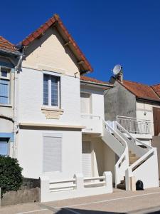 a white house with a staircase in front of it at Val 1er in Quend-Plage
