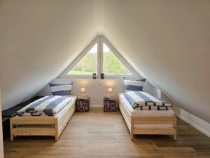 2 Betten in einem Dachzimmer mit Fenster in der Unterkunft Ferienhaus Liv in Biendorf