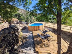 a wooden deck with a hot tub and a chair at Nidos del Buitre - Apartamentos Rurales in Valencia de Alcántara