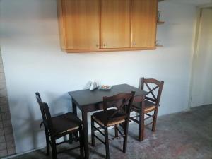 a dining room table with four chairs and a cabinet at Γκαρσονιέρα δίπλα στην θάλασσα κ θέα στο λιμανι in Évdhilos