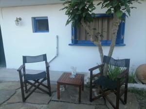 two chairs and a table in front of a house at Γκαρσονιέρα δίπλα στην θάλασσα κ θέα στο λιμανι in Évdhilos +2 photos