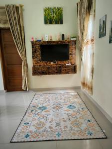 a living room with a television and a rug at Jirek Homestay Bukittinggi in Bukittinggi +9 photos