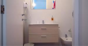 a bathroom with a sink and a toilet and a mirror at Antica Muraglia Apartments in Molfetta