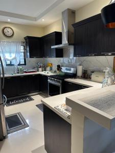 a kitchen with black cabinets and a clock on the wall at Villa Christine in Ocho Rios