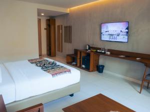 a hotel room with a bed and a tv on the wall at Kambaniru Beach Hotel and Resort in Waingapu