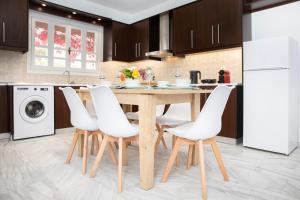 a kitchen with a wooden table and white chairs at ChrisAri House in Zipárion