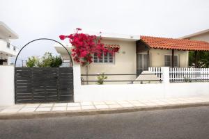 ein weißer Zaun mit einem schwarzen Tor mit Blumen darauf in der Unterkunft ChrisAri House in Zipárion
