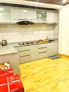 a kitchen with white cabinets and a wooden floor at Nehal Royal Homestay in Kalimpong