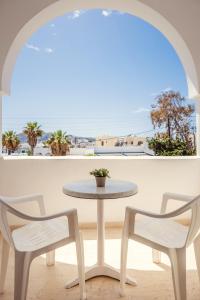 stół i dwa krzesła przed oknem w obiekcie Cyclades Hotel w mieście Karterados