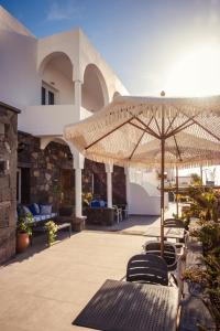 patio ze stołem, krzesłami i parasolem w obiekcie Cyclades Hotel w mieście Karterados