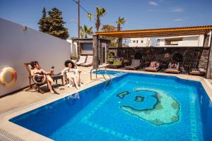 a group of people sitting around a swimming pool at Cyclades Hotel in Karterados