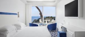 a hotel room with a bed and a tv and a table at Hotel Scalinatella in Capri