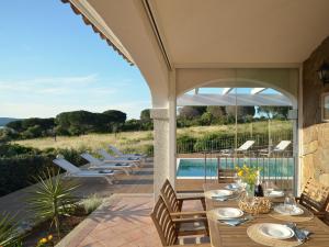 a patio with a table and chairs and a pool at Villa Allegria, romantic luxury 300m from the beach, heated pool, firepit and sauna in Tanaunella