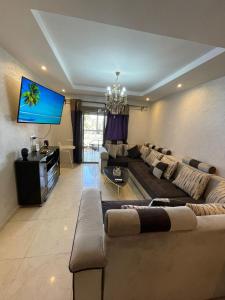 a living room with a large couch and a flat screen tv at Appartement de rêve à Marrakech in Marrakech