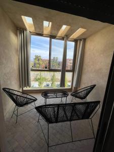 a room with four chairs and a large window at Appartement de rêve à Marrakech in Marrakech