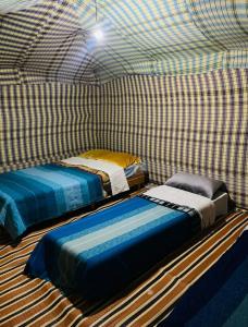 メルズーガにあるMerzouga Nomad Campの市松模様の部屋にベッドが2つある部屋