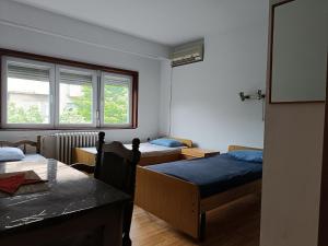 a room with two beds and a table and a window at Mlin Balkan Rooms in Skopje
