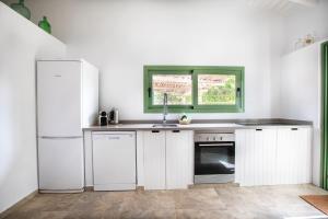 サン・フランセスク・ハヴィエルにあるCasa Can Joan Guaschの白いキャビネット、シンク、冷蔵庫付きのキッチンが備わります。