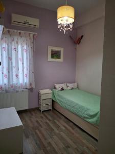 a small bedroom with a green bed and a chandelier at Komi Blue in Kómi