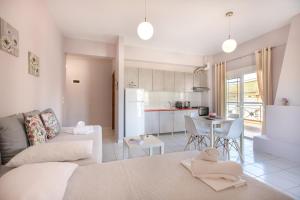 ein weißes Wohnzimmer mit einem Sofa und einer Küche in der Unterkunft Almyra Apartments by RentalsPro - Hanioti Halkidiki in Chaniotis